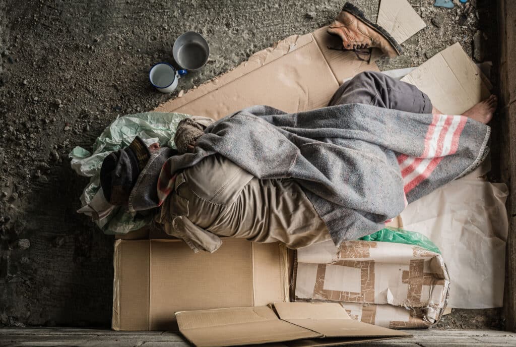 Homeless man sleeping on boxes.